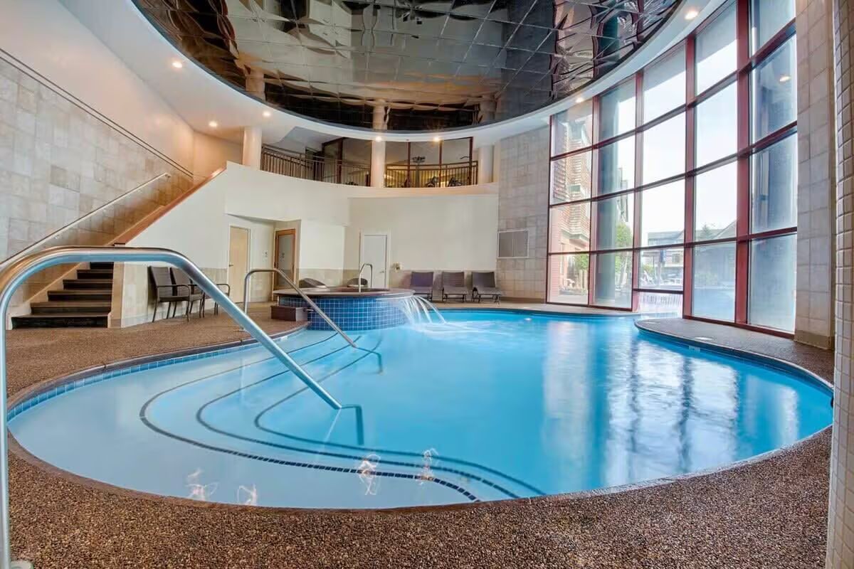 Ein hallenbad mit gewölbtem Design, einer Treppe und Blick durch große Fenster nach draußen.