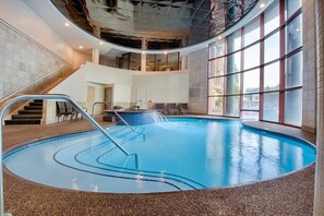An indoor swimming pool with a curved design, a staircase, and a view of the outside through large windows. - Deluxe 2BR at Wyndham Long Wharf Resort -walk to downtown - 2.3 miles from Beach (Newport)