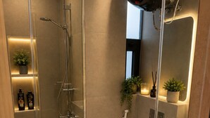 Ein modernes Badezimmer mit einer gläsernen Duschkabine, einer weißen Toilette und einem Spiegel über dem Waschbecken.