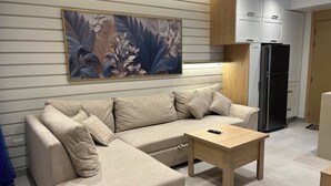 Ein modernes Wohnzimmer mit einem beigefarbenen Ecksofa, einem Holztisch und einem großen floralen Kunstwerk an der Wand.