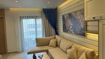Un salon moderne avec un canapé beige, une petite table en bois et une grande œuvre d’art florale accrochée au mur.