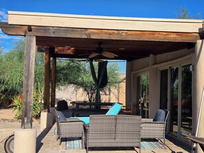 An outdoor patio with wicker furniture, a ceiling fan, and a view of the backyard.