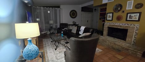 A living room with a fireplace, a sofa, a coffee table, and a lamp.