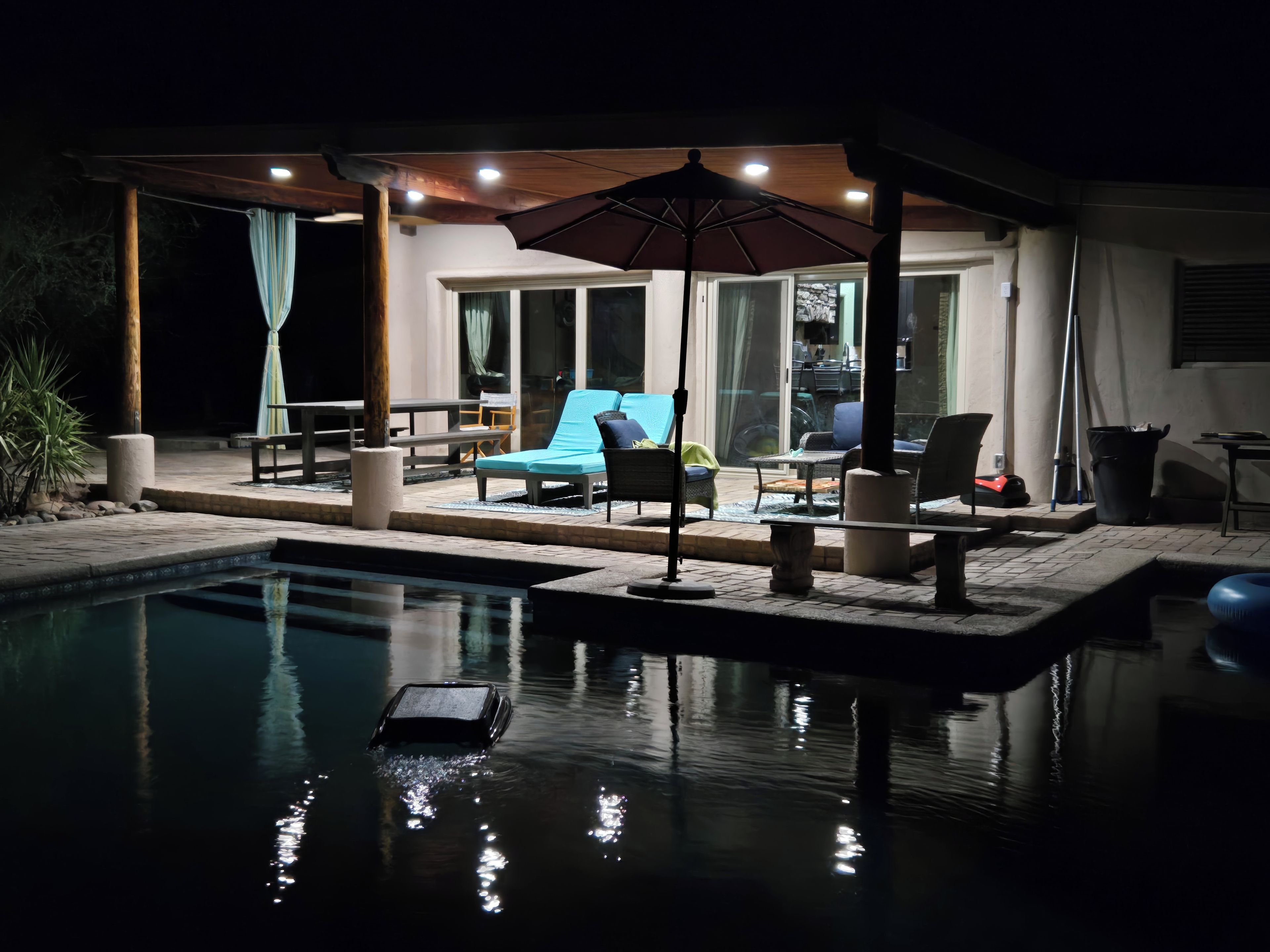 Un espace aménagé au bord de la piscine, avec des chaises longues, une table et un coin salon abrité pour le soir.