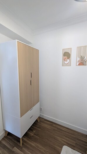 Ein Zimmer mit Kleiderschrank, Holzboden und zwei Wandbildern.