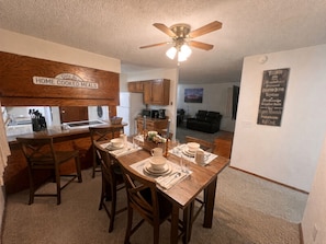 A dining area with a wooden table set for four, a ceiling fan, and a kitchen in the background. - 2-bedroom condo in quiet, charming Delta, CO (Delta)