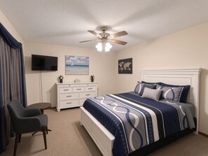 A bedroom with a bed, a dresser, a chair, a ceiling fan, a TV, and wall art. - 2-bedroom condo in quiet, charming Delta, CO (Delta)