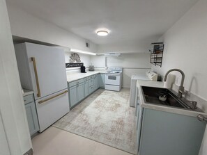 A compact kitchen with white appliances, a built-in oven, and a sink with a faucet.