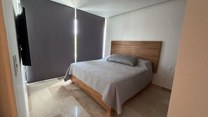 Ein Schlafzimmer mit einem Bett, einem Holz-Kopfteil und einer grauen Wand.