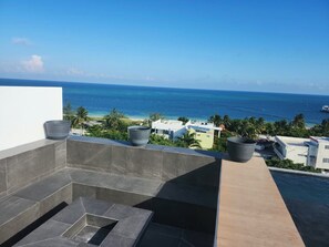Eine Dachterrasse mit Blick auf das Meer, einem Pool und umliegenden Gebäuden.