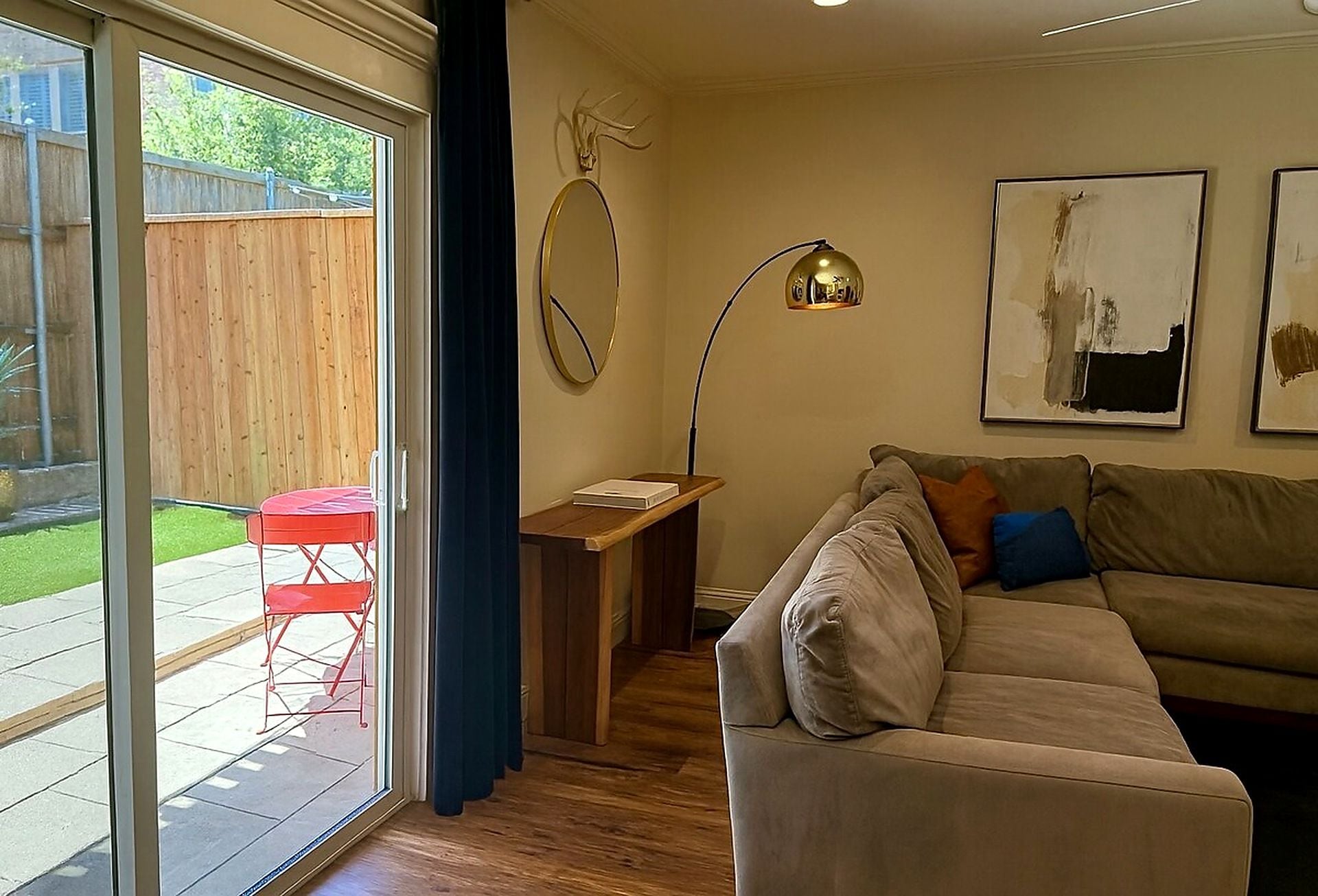 A living room with a sofa, a red chair, a table, a lamp, and a window.
