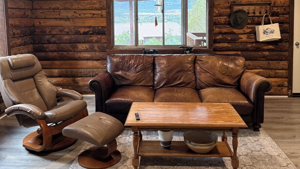A log cabin interior with a leather recliner, a leather sofa, and a wooden coffee table. - Peaceful 2 bedroom log cabin in Durango perfect for a relaxing getaway. Pets ok. (Durango)