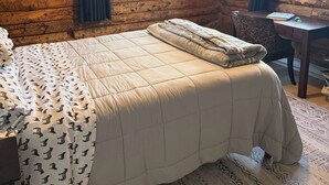 A log cabin-style room with a bed, a desk, and a window with curtains. - Peaceful 2 bedroom log cabin in Durango perfect for a relaxing getaway. Pets ok. (Durango)