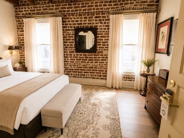 Een hotelkamer met een bakstenen muur, een groot bed, een dressoir en een spiegel.