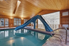 An indoor swimming pool with a blue slide and stairs leading to a higher level. - Private 35-Acre Resort Near Wisconsin Dells - Indoor Pool, Golf Sim, Sleeps 30+ (Camp Douglas)