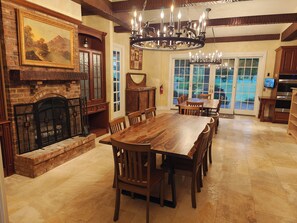 A spacious dining area with a large wooden table and chairs, a fireplace with a stone surround, and a chandelier. - Private 35-Acre Resort Near Wisconsin Dells - Indoor Pool, Golf Sim, Sleeps 30+ (Camp Douglas)