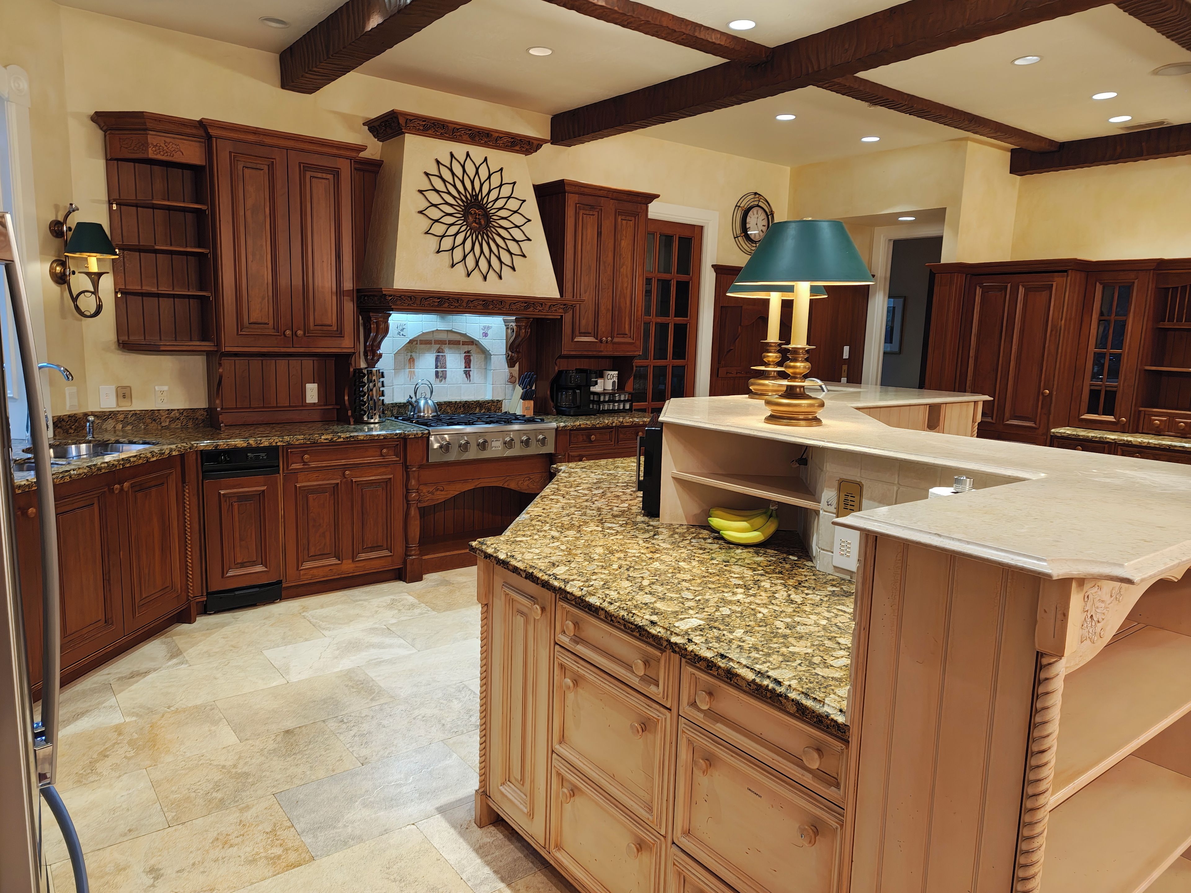 A kitchen with wooden cabinets, granite countertops, and a central island.