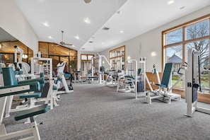 A gym with various exercise machines, large windows, and a ceiling fan. - Private 35-Acre Resort Near Wisconsin Dells - Indoor Pool, Golf Sim, Sleeps 30+ (Camp Douglas)