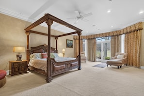 A four-poster bed with a canopy, a sitting area with a chair, and a view through a glass door. - Private 35-Acre Resort Near Wisconsin Dells - Indoor Pool, Golf Sim, Sleeps 30+ (Camp Douglas)