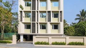 Um edifício residencial com vários andares, fachada simétrica, diversas varandas e portão.