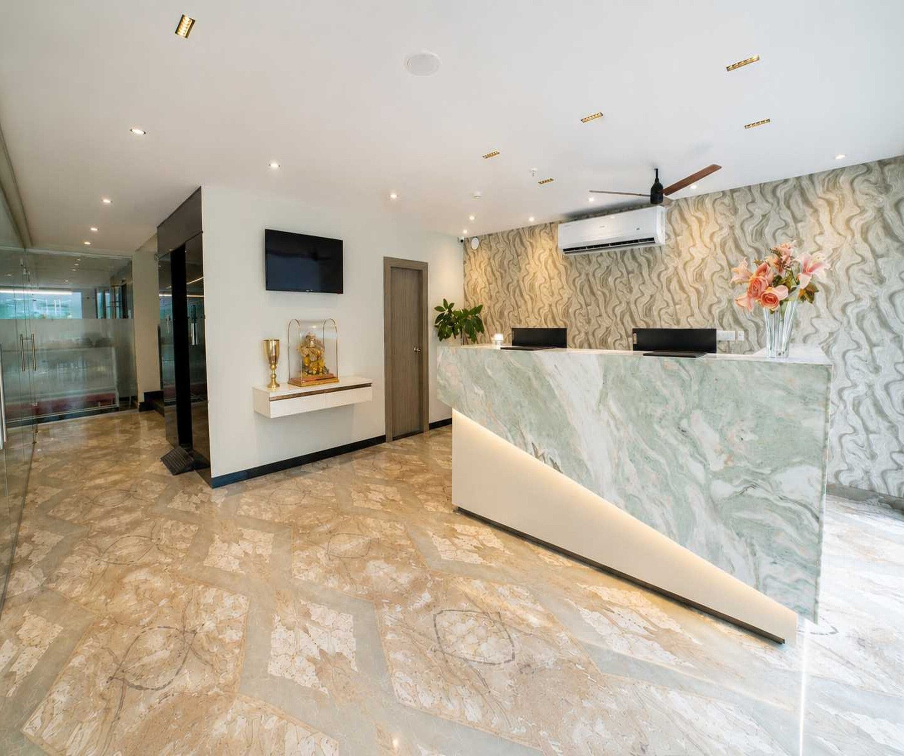 A reception area with a marble counter, a ceiling fan, and a patterned wall.