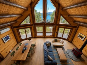 A log cabin interior with a dining area, seating, and a fireplace.