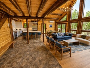 A spacious room with a stone floor, wooden furniture, and large windows.