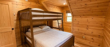 Ein hölzernes Etagenbett in einem Blockhausszimmer mit geneigter Decke und Holzvertäfelung.