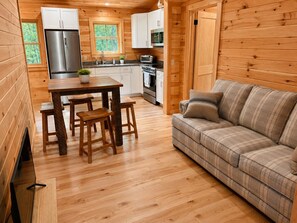 A wooden interior with a dining area, sofa, and kitchen. - Luxury Private waterfront escape on Moosehead Lake with trail access, sleeps 15+ (Greenville)