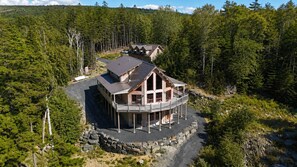 A large, multi-story lodge with a balcony, surrounded by dense forest.