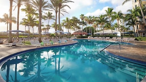 Une piscine avec des chaises longues et des palmiers.