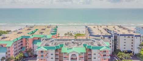 A beachfront hotel with multiple buildings, a parking lot, and a beach area.
