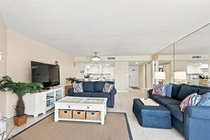 A modern living room with a flat-screen TV, two sofas, a coffee table, and a kitchen in the background. - Modern Ocean View Escape (Indian Shores)