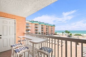 A balcony with a view of a beach and a hotel building. - Modern Ocean View Escape (Indian Shores)