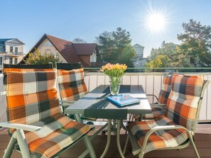 A deck with a table and chairs, a book, and a vase with flowers. - Holiday Apartment With 1 Bedroom (Heringsdorf)