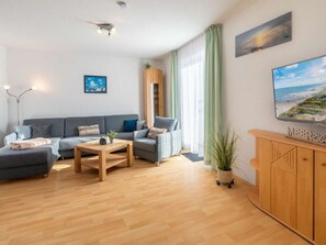 A modern living room with a sofa, a coffee table, and a TV on a wooden cabinet. - Holiday Apartment With 1 Bedroom (Heringsdorf)
