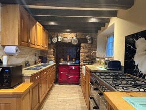 Une cuisine avec des meubles de rangement en bois, un fourneau rouge et une cuisinière à gaz.