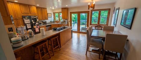 A spacious kitchen with wooden cabinets, a central island with stools, and a dining area with chairs.