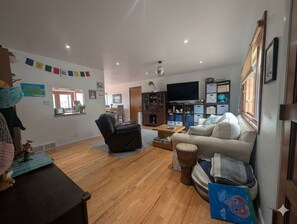 Uma sala de estar com sofá, poltrona, mesa de centro e televisão.