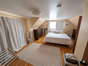 A bedroom with a bed, a dresser, a nightstand, a radiator, and a window with curtains. - Spacious 4 bedrooms 2 bath rental near bus line Sundance Film Festival 2027 (Boulder)