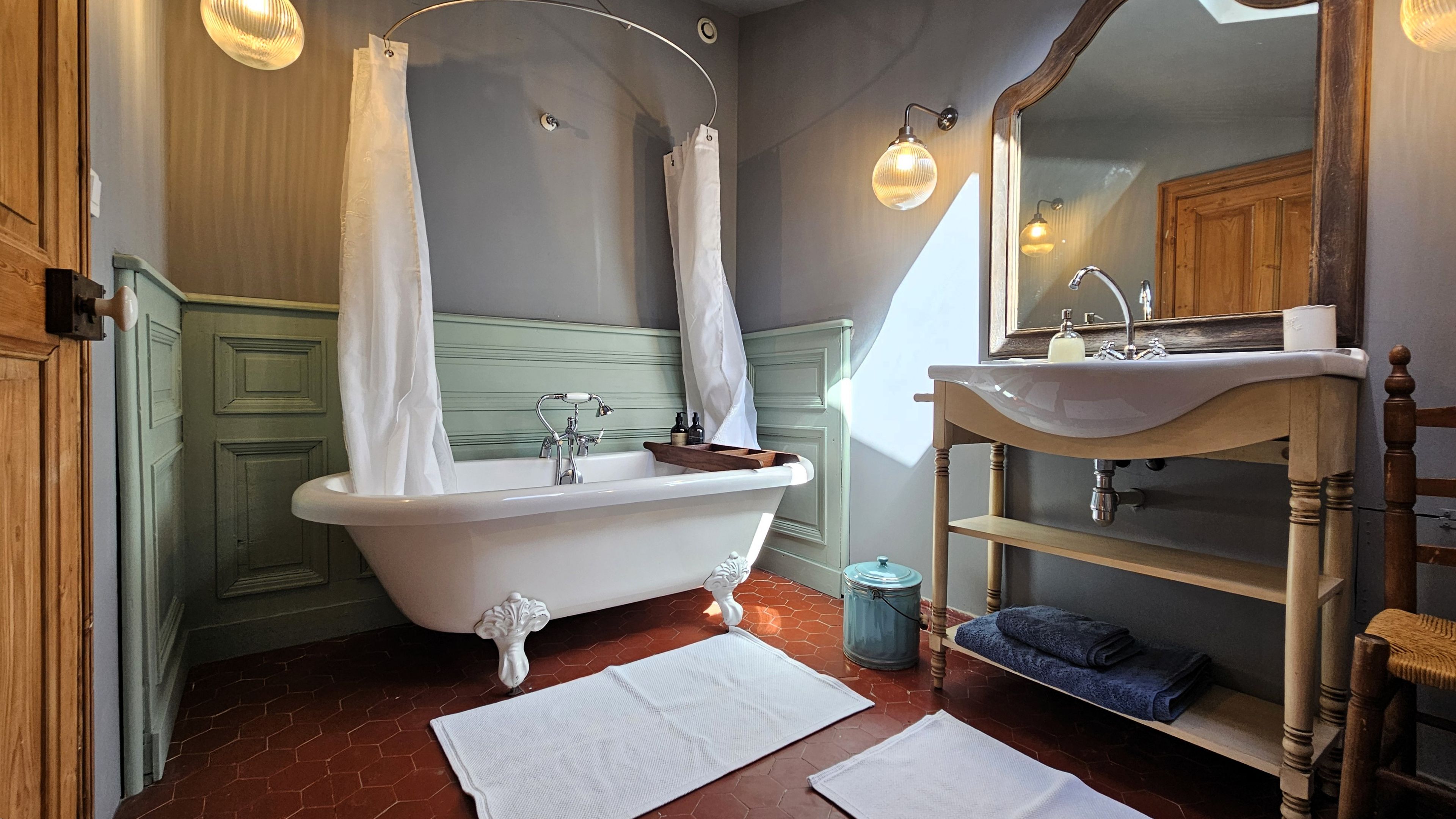 A bathroom with a freestanding bathtub, a vanity with a mirror, and a shower curtain.