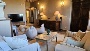 A living room with a television, sofas, a coffee table, and wall-mounted lamps. - Charming 3-bedroom house with panoramic views in peaceful Séguret (Séguret)