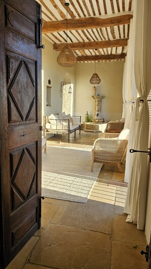 A room with a bed, a wicker chair, a stone floor, and a wooden ceiling. - Charming 3-bedroom house with panoramic views in peaceful Séguret (Séguret)