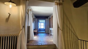 A hallway with a radiator, a table, and a window leading to a room. - Charming 3-bedroom house with panoramic views in peaceful Séguret (Séguret)