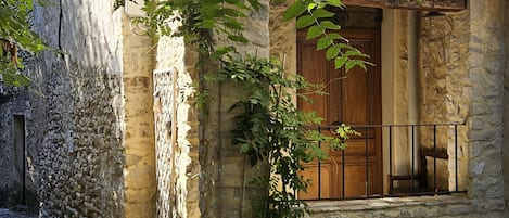 Un edificio de piedra con una puerta de madera y una ventana, rodeado de adoquines.