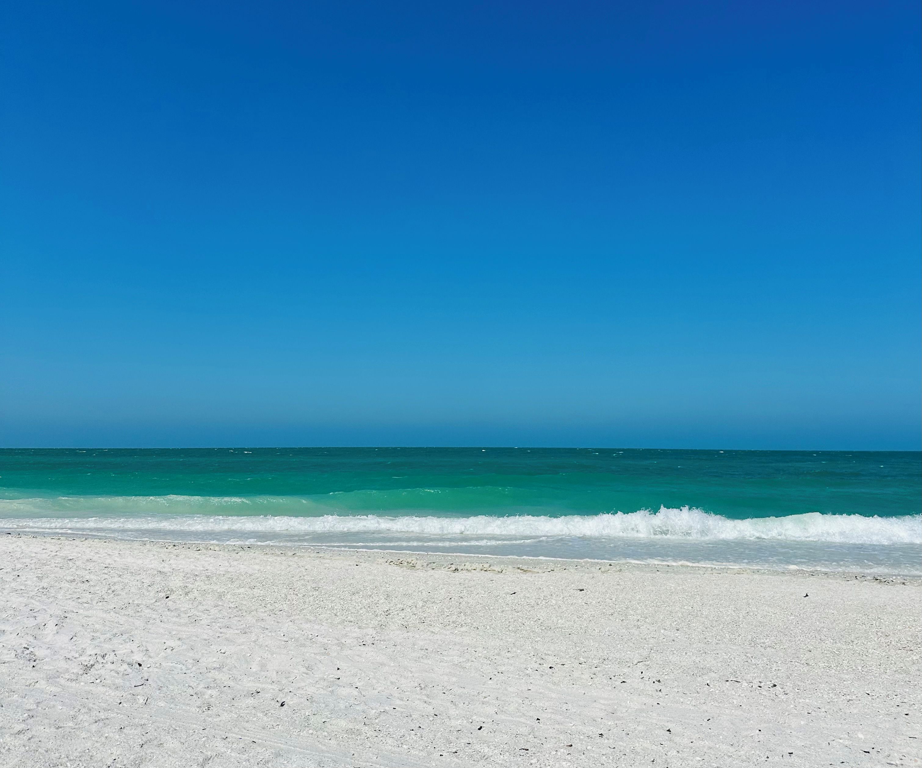 Una playa con arena blanca y agua azul cristalina.