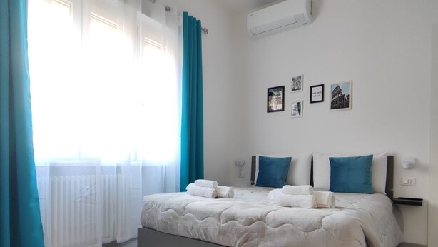 Een slaapkamer met een bed, gordijnen en foto's aan de muur.