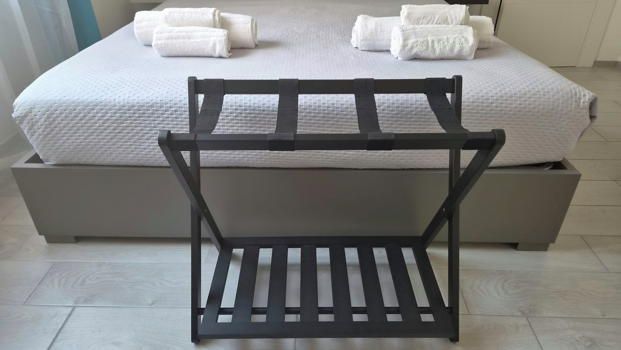 A bed with white bedding and rolled white towels.