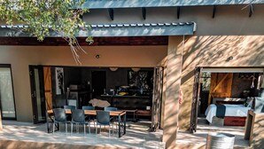A pool area with a hot tub, a dining area with chairs, and a bed with a view. - Luxury Bush Villa | Private Pool, Hot Tub in Marloth at the Kruger National Park (Marloth Park)