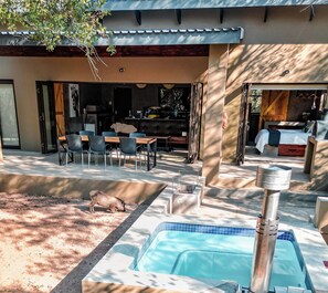 A pool area with a hot tub, a dining area with chairs, and a bed with a view. - Luxury Bush Villa | Private Pool, Hot Tub in Marloth at the Kruger National Park (Marloth Park)